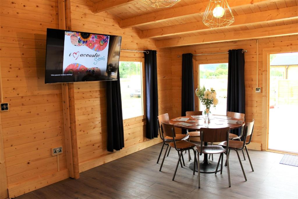 a dining room with a table and chairs and a tv at Inviting 3-Bedroom Lodge in Ashton Under Hill in Evesham