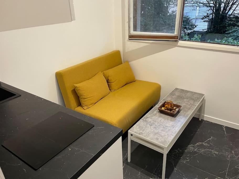 un canapé jaune dans une pièce avec une table dans l'établissement Studette cosy entièrement rénovée, à Paris