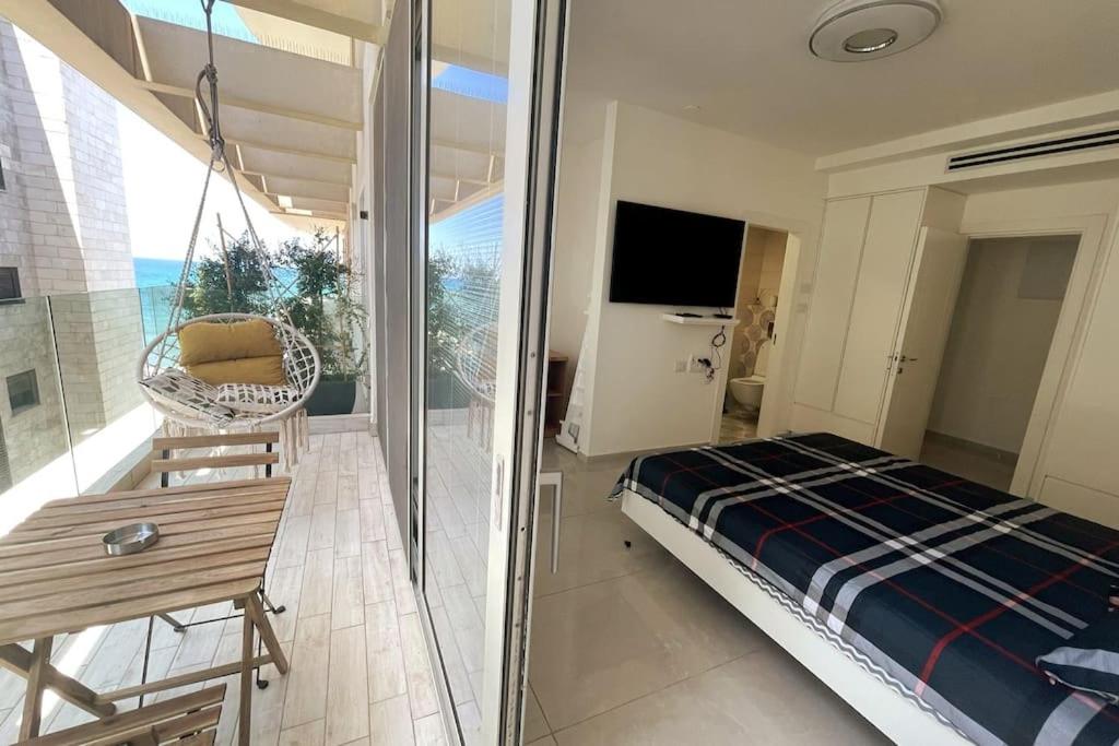 1 dormitorio con 1 cama y balcón con TV en luxury boutique apartment 2BR With balcony on the sea, en Haifa