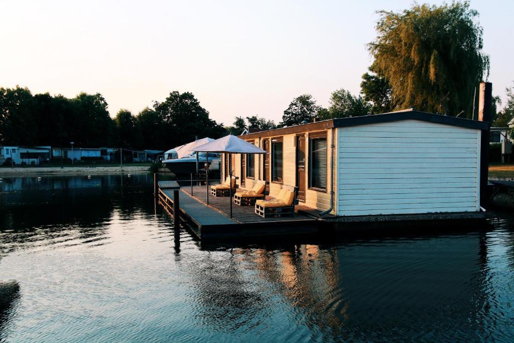 a small house on a dock on a body of water at Floatel - de Schans Alphen in Benedeneind