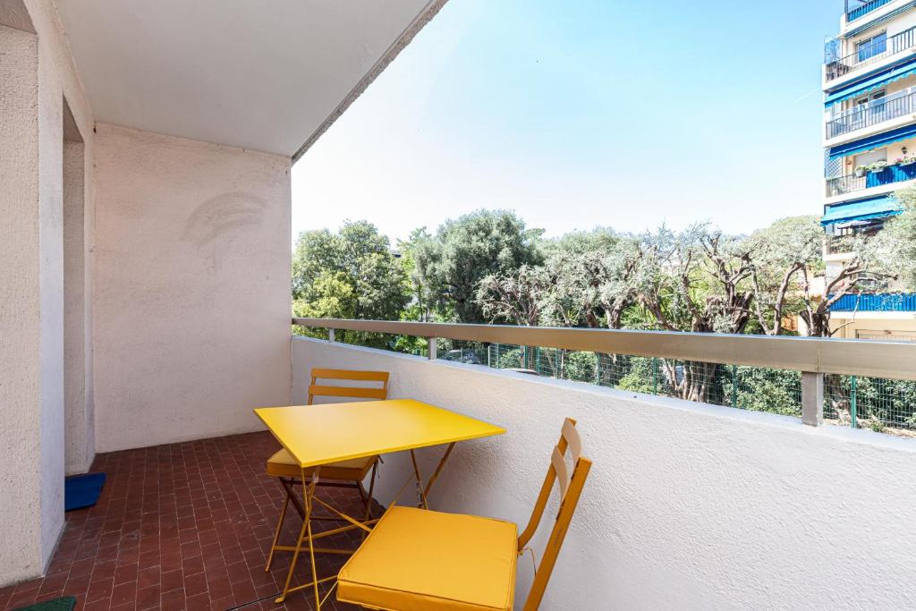 a yellow table and chairs on a balcony with a window at Martelly furnished flat in Antibes