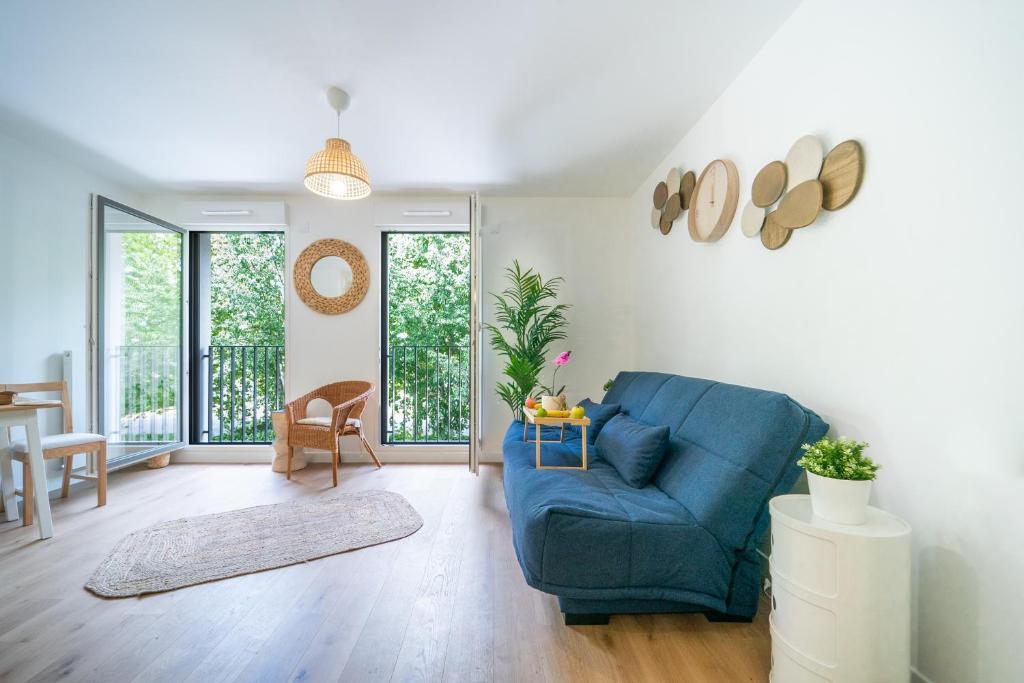 a living room with a blue couch and a table at Sensations - Studio dans le quartier daffaires in Rueil-Malmaison