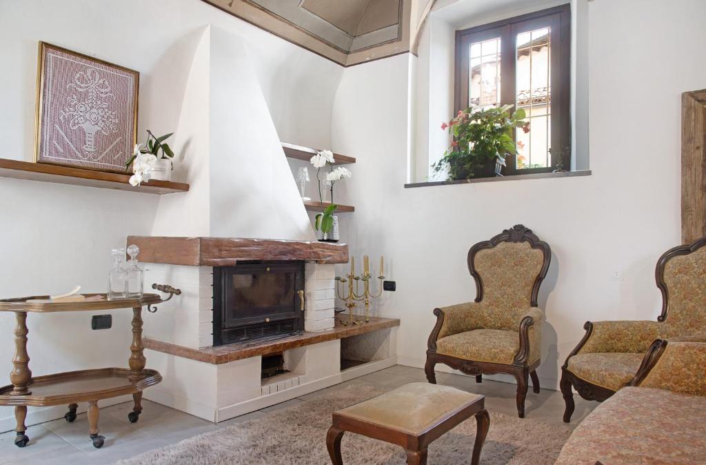 a living room with a fireplace and two chairs at Dimora Vittoria - Lago Maggiore in Casalzuigno