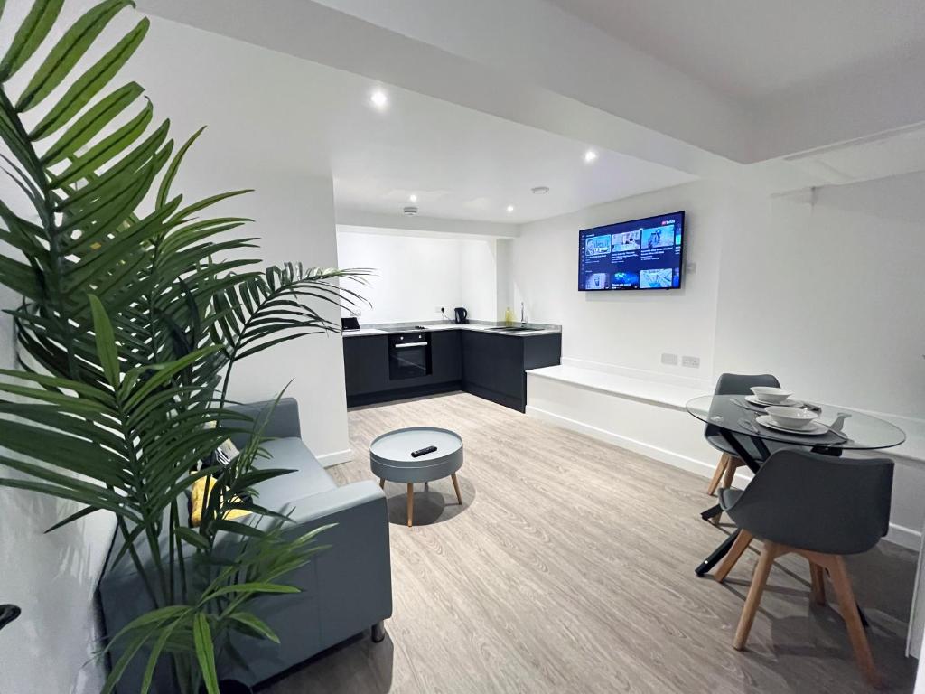 a living room with a potted plant and a kitchen at BL 1 Bedroom Apartment, Town Centre, Secure gated parking option, Modern, fresh and spacious living, Netflix ready TV, Wifi in Wellingborough