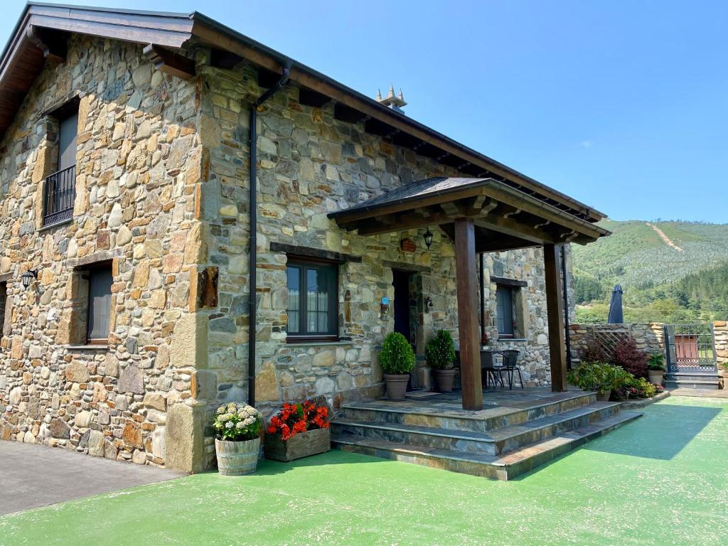 a stone house with a porch with flowers in front at Apartamentos Rurales Posada de las Hoces in Bustiello de Paredes