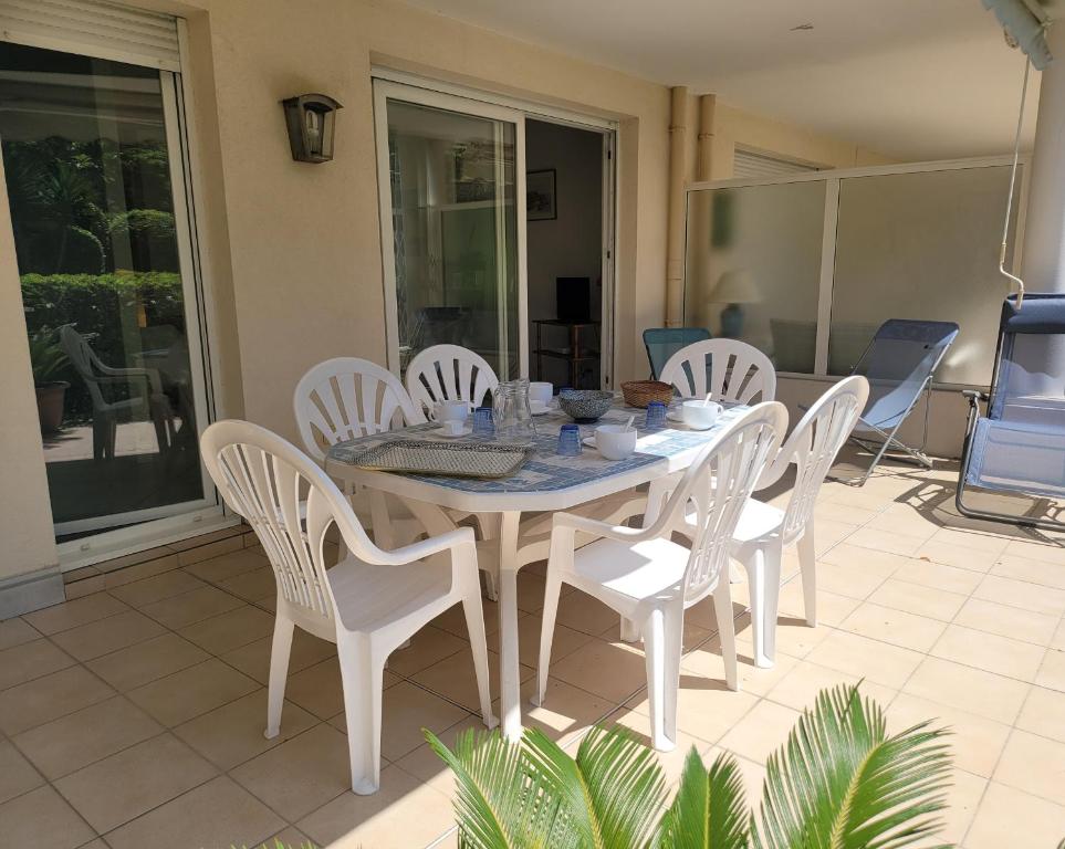 Une table à manger blanche et des chaises sont disponibles sur la terrasse. dans l'établissement LE 5 TANIT, à Antibes