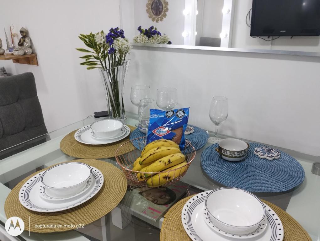 a table with plates and a bowl of bananas on it at Apartamento sector exclusivo acogedor in Bogotá
