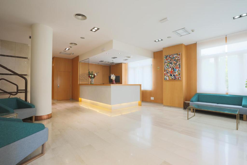 un hall avec des chaises bleues et un comptoir dans un bâtiment dans l'établissement Porcel Torre Garden, à Madrid