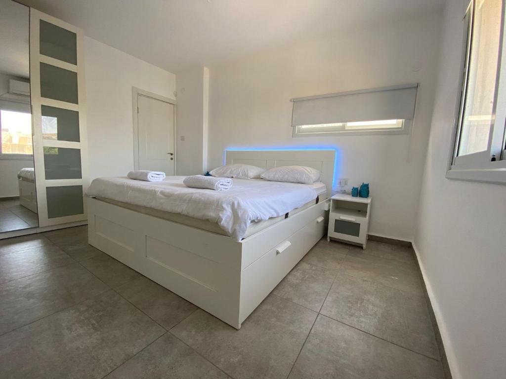 a bedroom with a white bed with a blue headboard at Romi's suite by LOREN VILLAGE in Neve Zohar