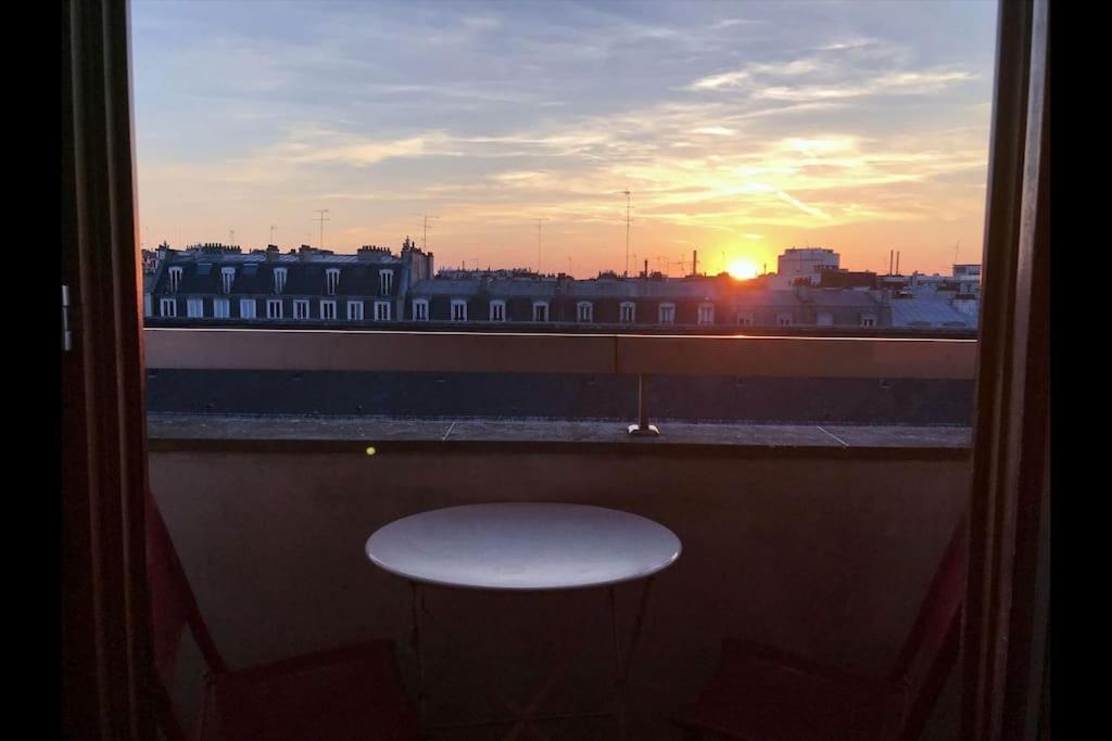 a view of the sunset from a window with a table at Le charme de Montmartre à ciel ouvert in Paris