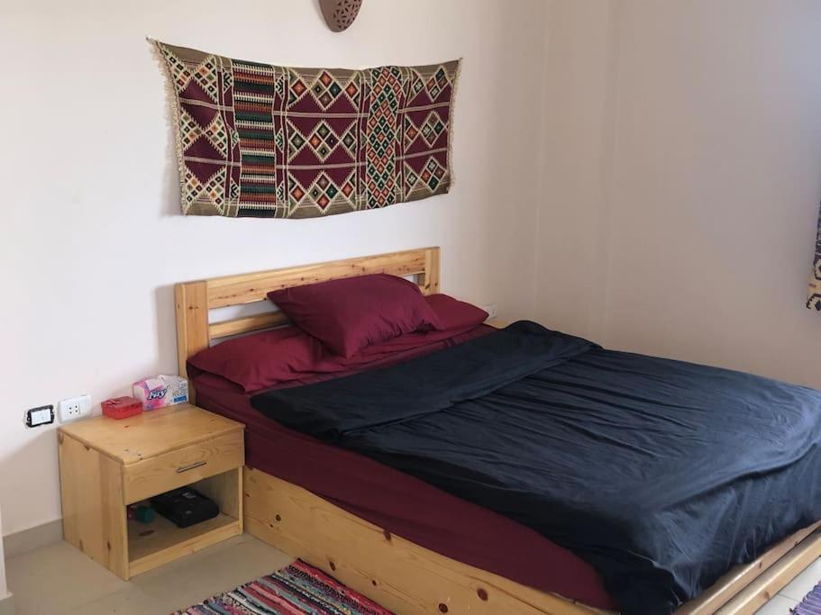 Dahab Relax Studio 3 في دهب: غرفة نوم مع سرير خشبي مع كومودينو وسيركس السرير