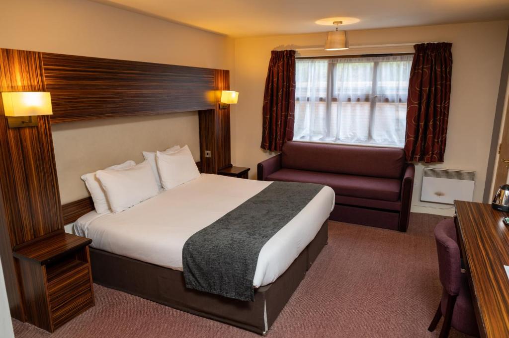 Habitación de hotel con cama y silla en The Fernhurst by Greene King Inns en Blackburn