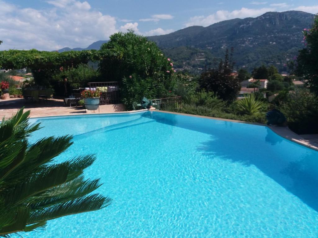 uma grande piscina azul com montanhas ao fundo em Gite Mireille em Carros