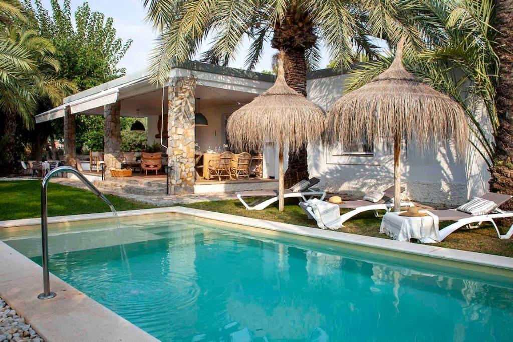 a swimming pool with chairs and a house at Villa Bonita en Alicante. in Elche