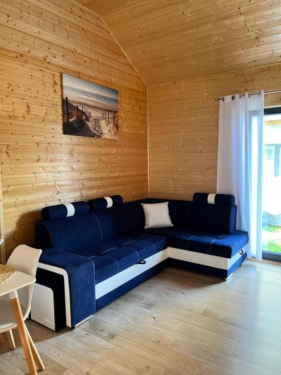 a blue couch in a room with a wooden wall at Domki Kapitan Antonio in Ustronie Morskie