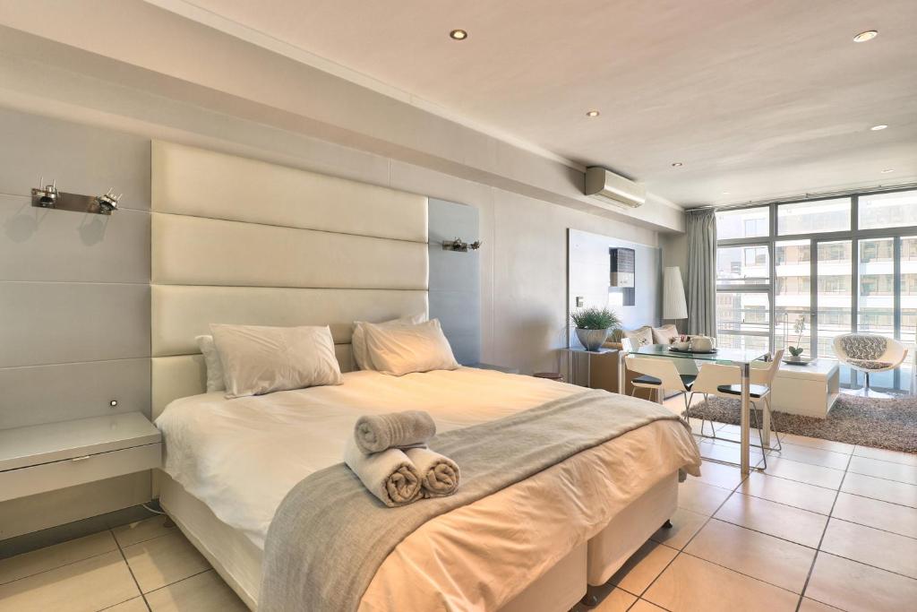 a bedroom with a large bed with a person laying on it at The Icon Studio Apartment 1000 in Cape Town