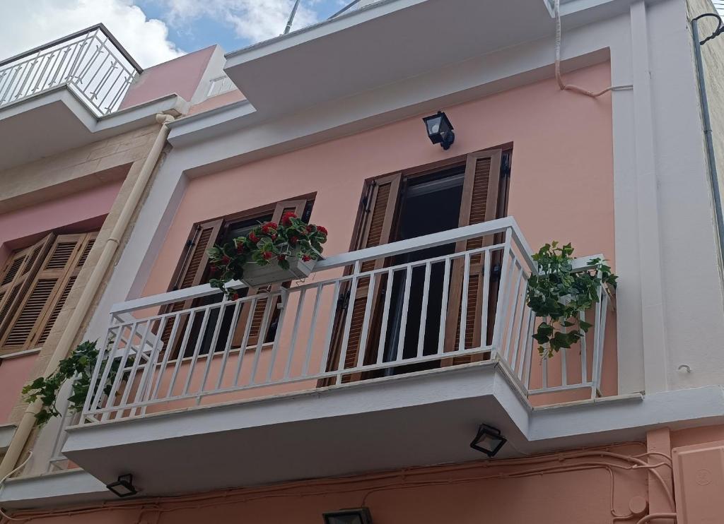 a pink house with potted plants on a balcony at Lefterakis place in Egina