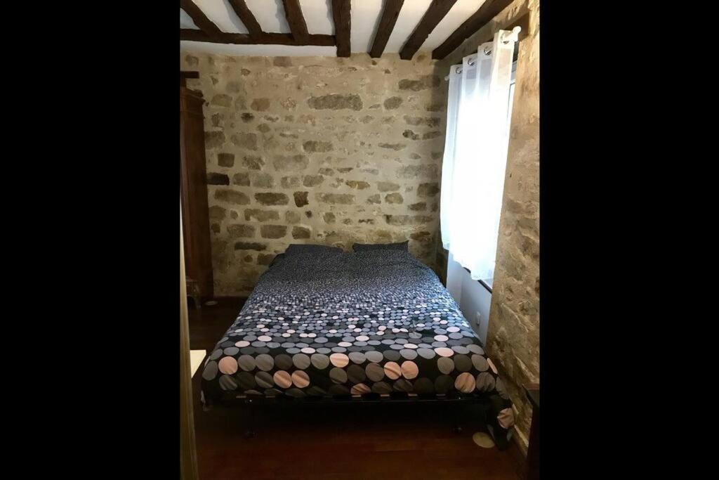 a small bed in a room with a brick wall at Charmant studio plein centre in Fontainebleau