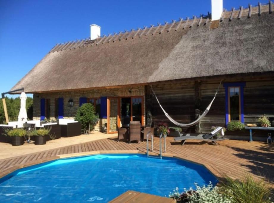 a house with a thatched roof and a swimming pool at Kadakamarja (Juniper) Residence 