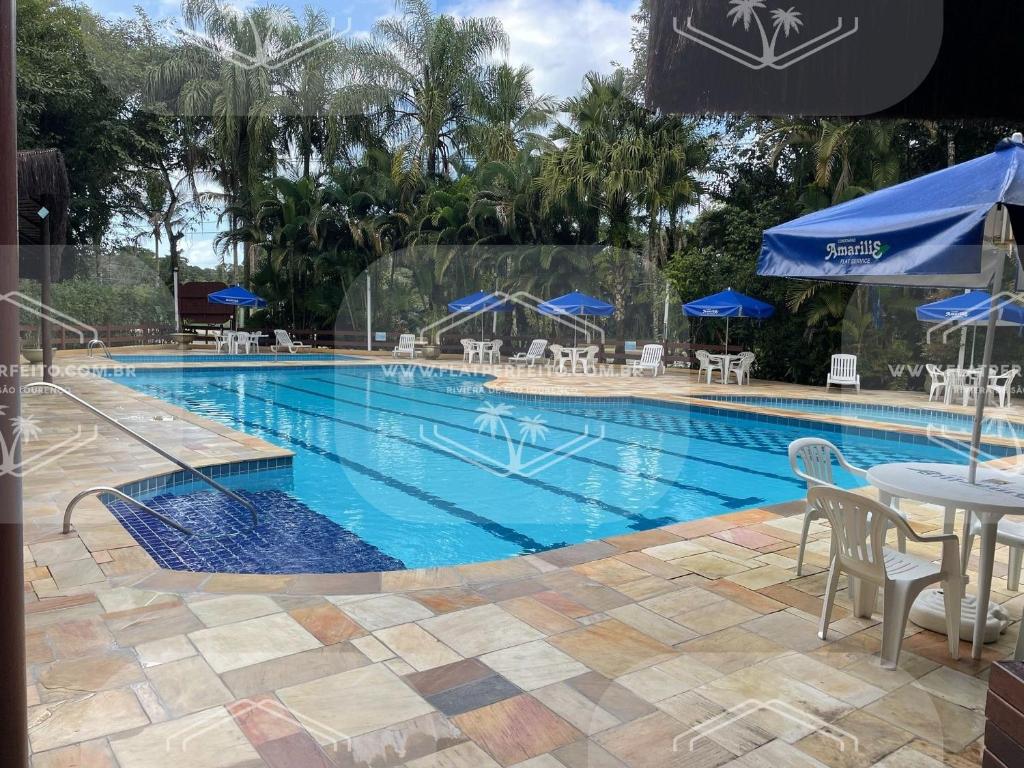 uma piscina com mesa e guarda-sóis azuis em Flat Perfeito Flat Amarilis em Riviera São Lourenço com café da manhã e enxoval completo praia e piscina com trocas em Riviera de São Lourenço