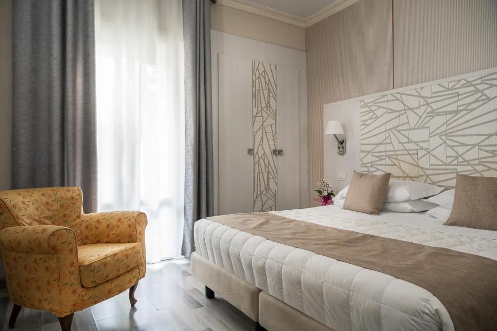 Grand Hotel Terme & SPA في تْشيانشانو تيرمي: غرفة نوم بسرير كبير وكرسي