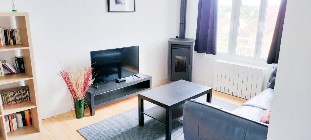 ein Wohnzimmer mit einem TV, einem Tisch und einem Sofa in der Unterkunft LE PERCHOIR in Corbeil-Essonnes