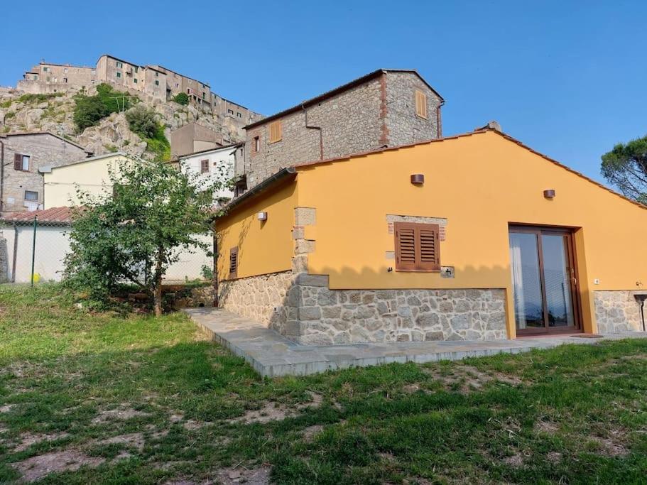 a yellow house with a hill in the background at Casa Fonte in Roccastrada
