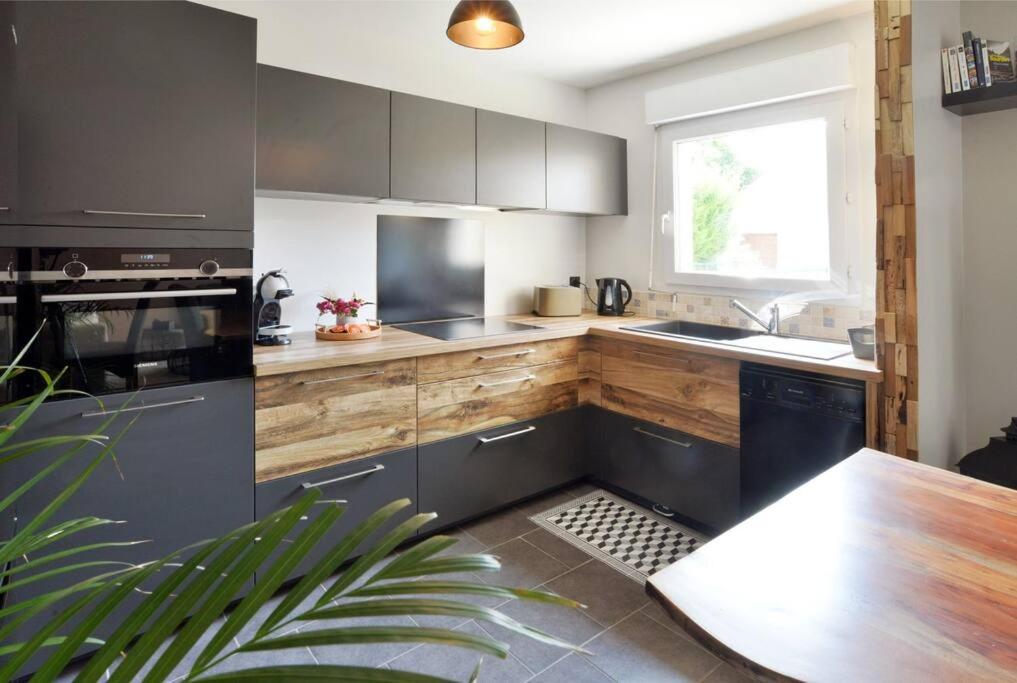 a kitchen with black and white cabinets and a table at Bonsaï Disneyland JO Paris 2024 avec Parking in Bailly-Romainvilliers