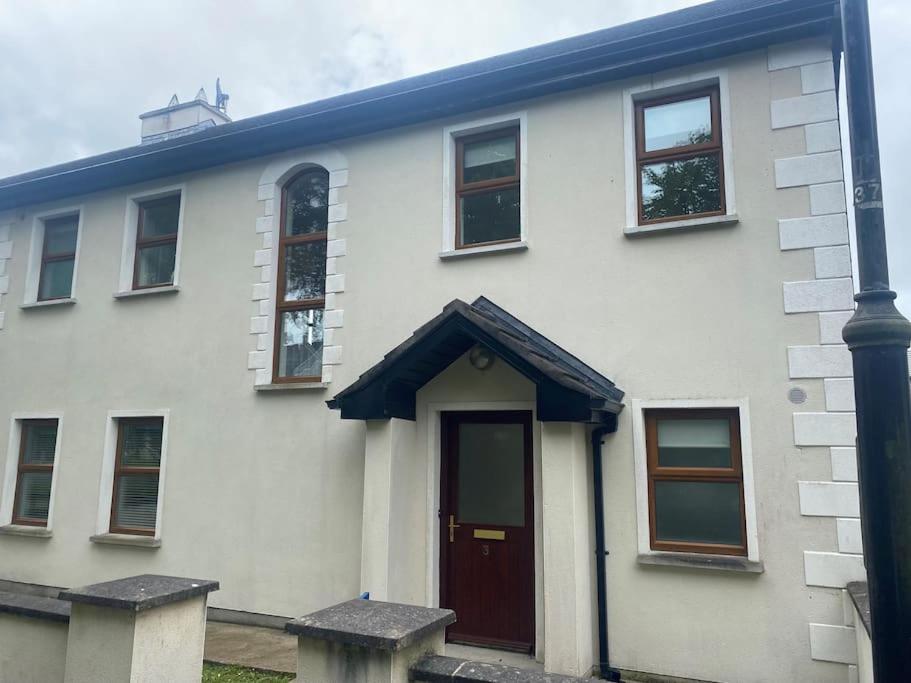 ein weißes Haus mit einer roten Tür und einer Stange in der Unterkunft Beautiful 3 Bedroom House in Coolaney Village County Sligo 