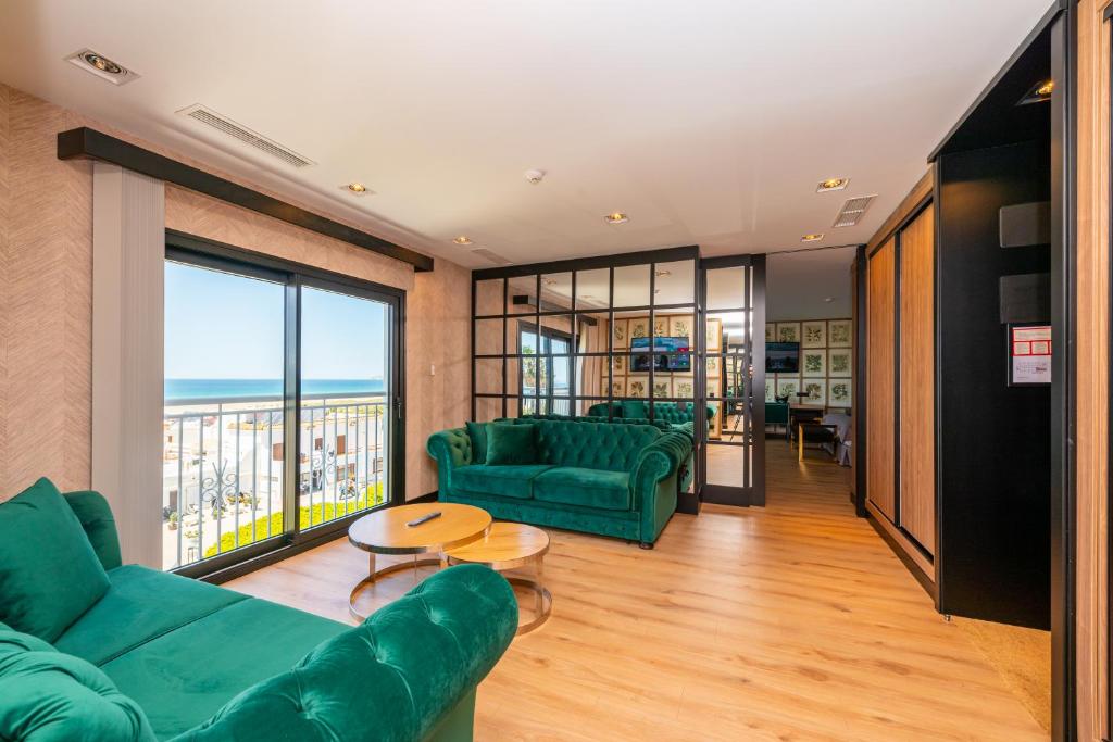 a living room with green furniture and a large window at Hotel Antonio II in Zahara de los Atunes