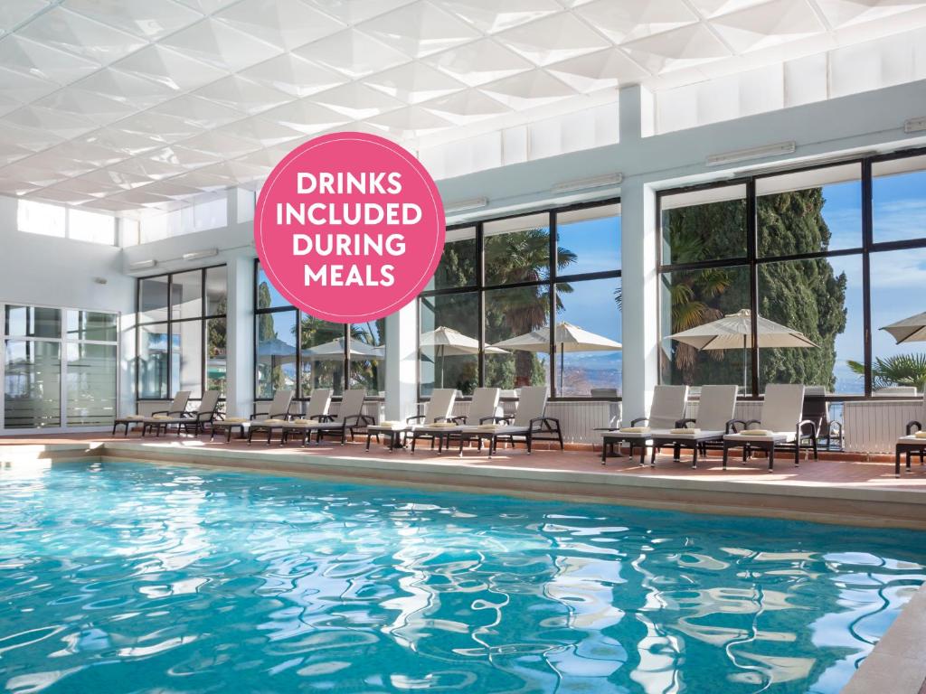 奧帕蒂亞的住宿－Hotel Kristal - Liburnia，游泳池,上面有标志,上面写着用餐时邀请的饮料
