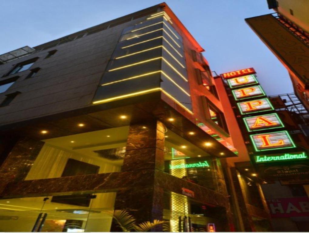 a tall building with neon signs in front of it at Hotel Uppal International,,,,We strive only for the Best in New Delhi