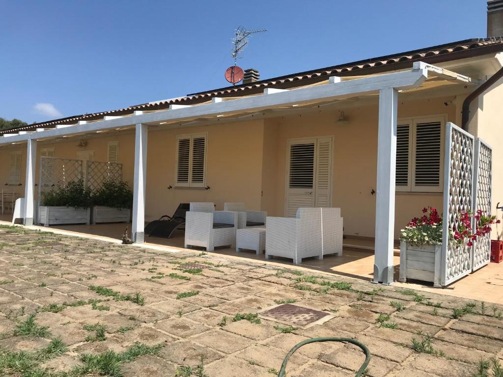 a patio with white chairs and a pergola at Casa Il Girasole in Marina di Grosseto