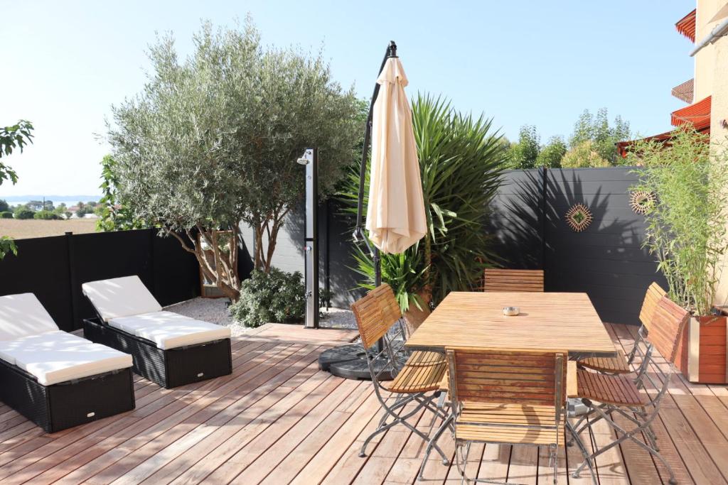 eine Terrasse mit einem Tisch, Stühlen und einem Sonnenschirm in der Unterkunft Le petit Sud in Carqueiranne