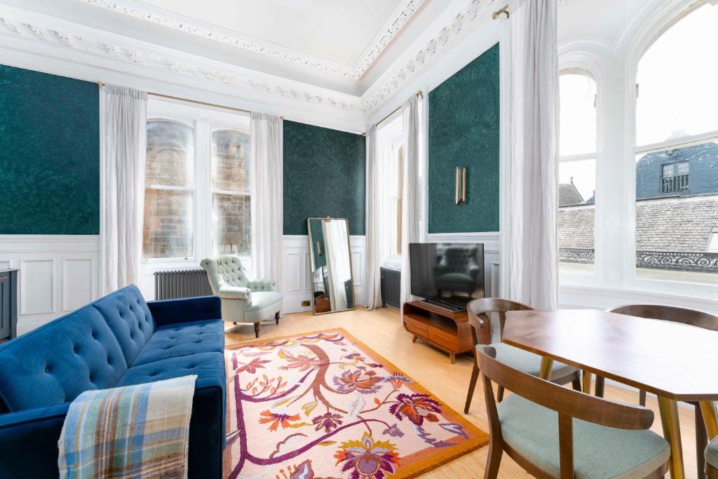 ein Wohnzimmer mit einem blauen Sofa und einem Tisch in der Unterkunft 89 The Merchants by The House of Danu in Edinburgh