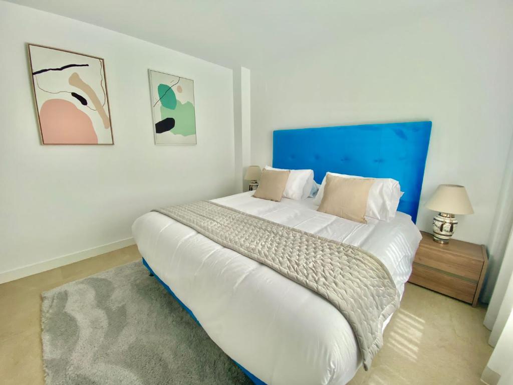 1 dormitorio con 1 cama blanca grande y cabecero azul en La Cala Golf - Luxury 3bed apartment - First line golf view, en La Mairena