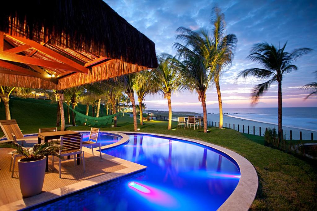 una piscina con tavolo e sedie vicino all'oceano di Carmel Charme Resort ad Aquiraz