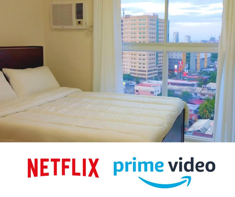 a bed in a bedroom with a view of a city at Cozy Place at Bamboo Bay Cebu in Cebu City