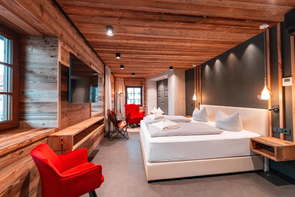 1 dormitorio con 2 camas y silla roja en Landgasthof & Hotel beim Lipp, en Rosshaupten