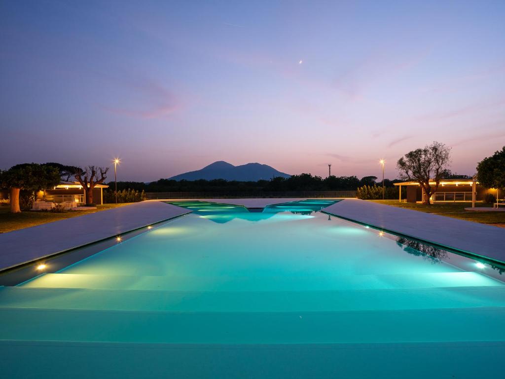 a swimming pool with blue water at night at Secret Garden Resort & Spa in Palma Campania