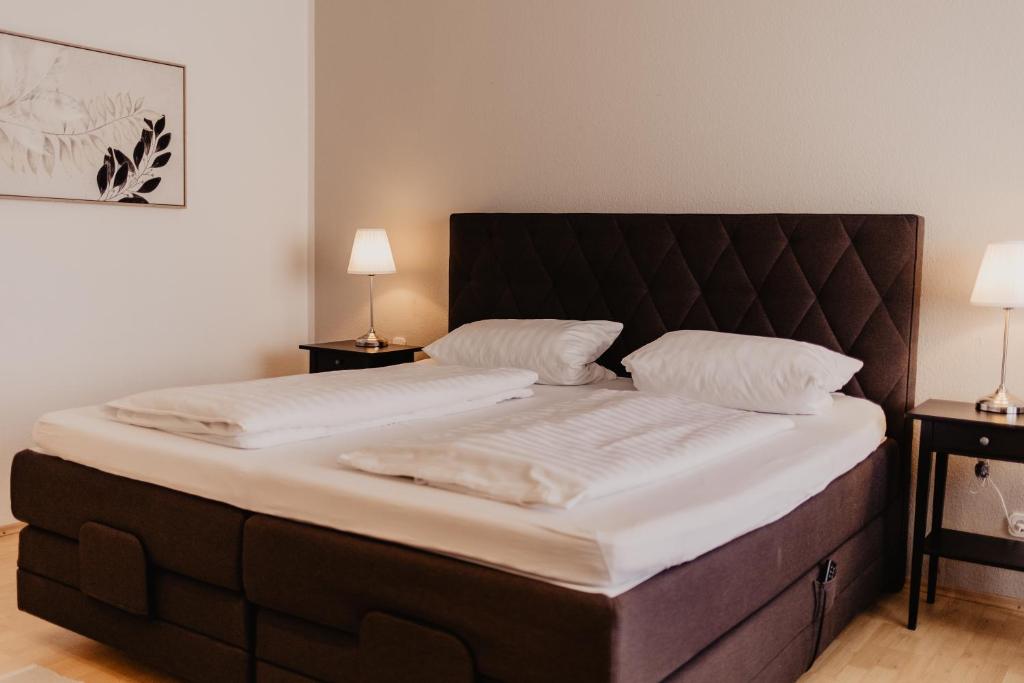 Cette chambre comprend un grand lit avec des draps blancs et 2 lampes. dans l'établissement Fährhaus Kollmar, à Kollmar
