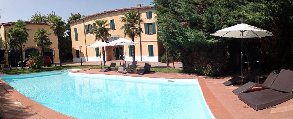 einen Pool mit Stühlen und einem Sonnenschirm neben einem Haus in der Unterkunft Villa delle palme B&B 5 stelle in Carpi
