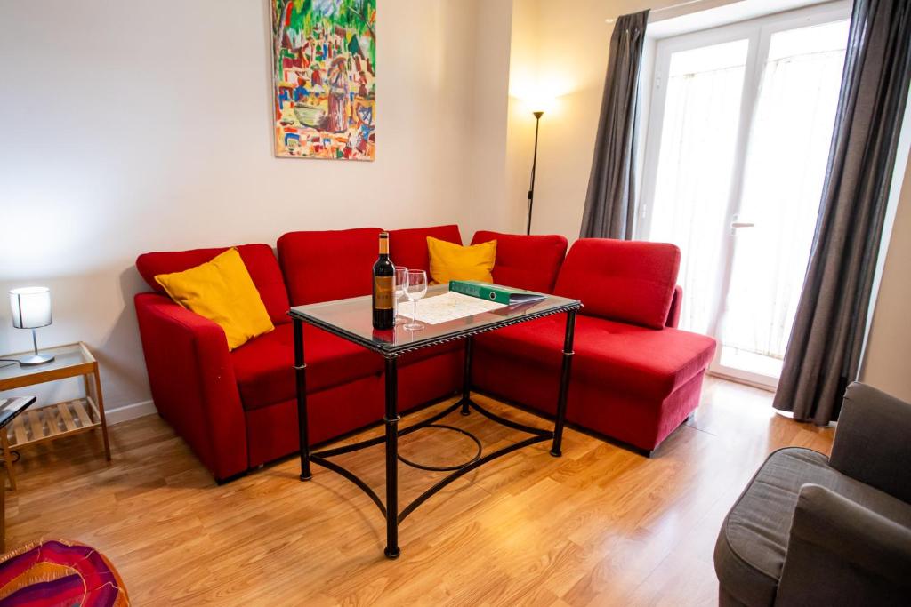 a living room with a red couch and a glass table at Apartamentos Doña Concha in Seville