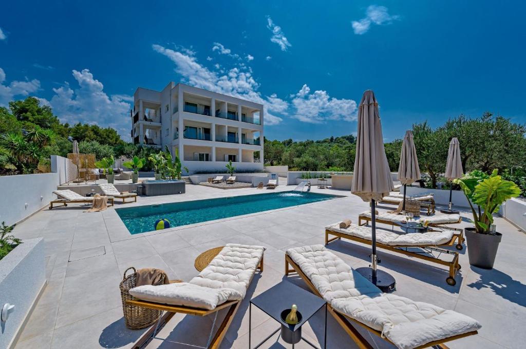 a pool with chairs and umbrellas next to a building at Luxury Villa Del Sogno with pool, jacuzzi, parking in Trogir