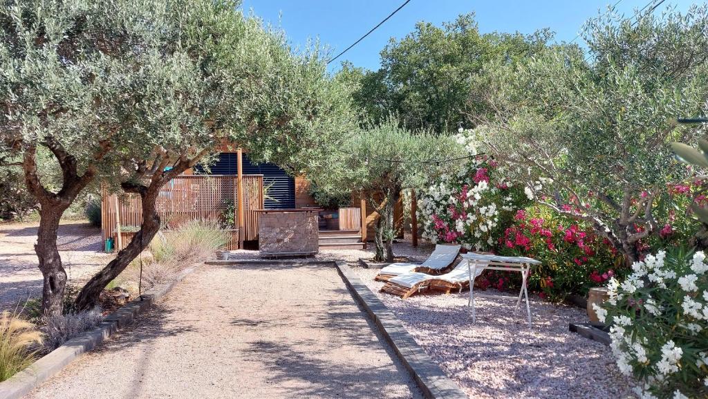 un jardín con un banco y algunos árboles y flores en Lodge Les Oliviers en Garéoult