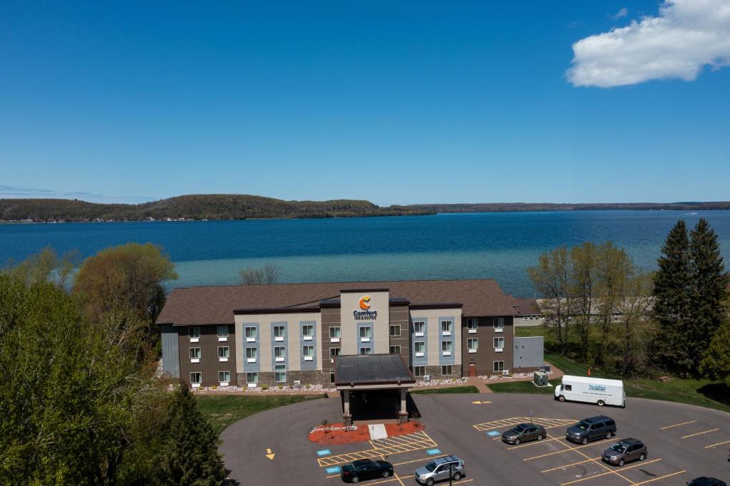 Comfort Inn & Suites Munising-Lakefront في مونيسينغ: اطلالة جوية على فندق مع موقف للسيارة