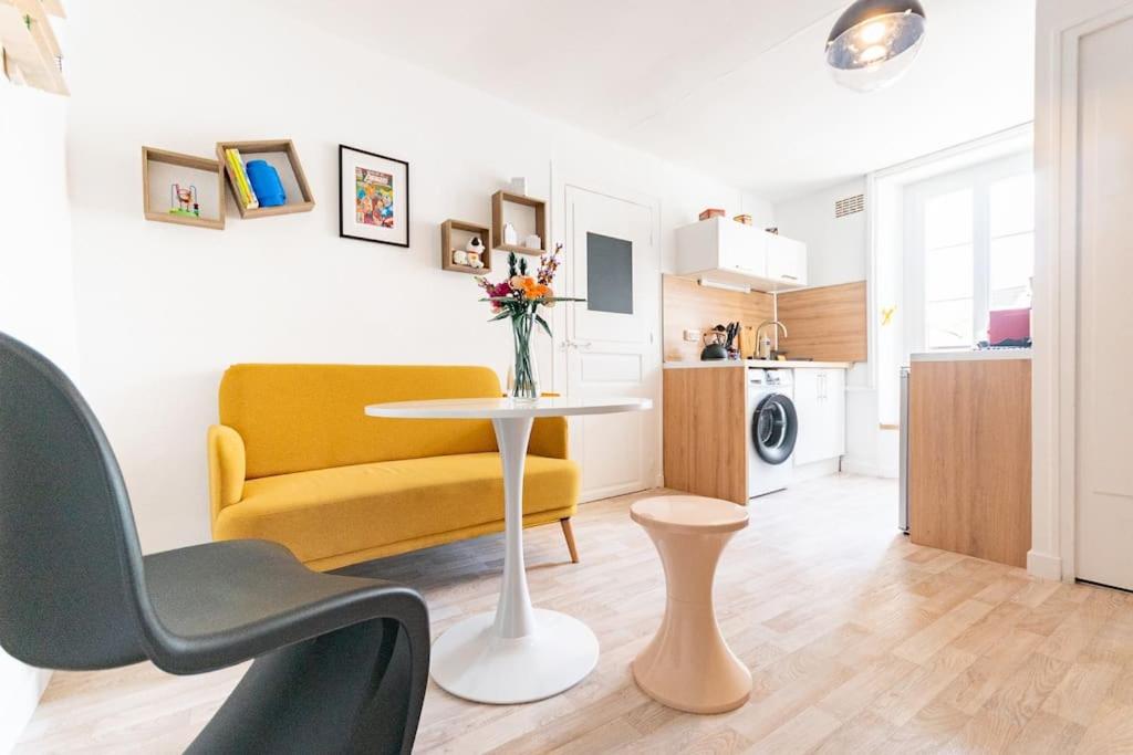 uma sala de estar com um sofá amarelo e uma mesa em Souvenirs d'enfance-La Bonne Marienne-La Madeleine em Angers