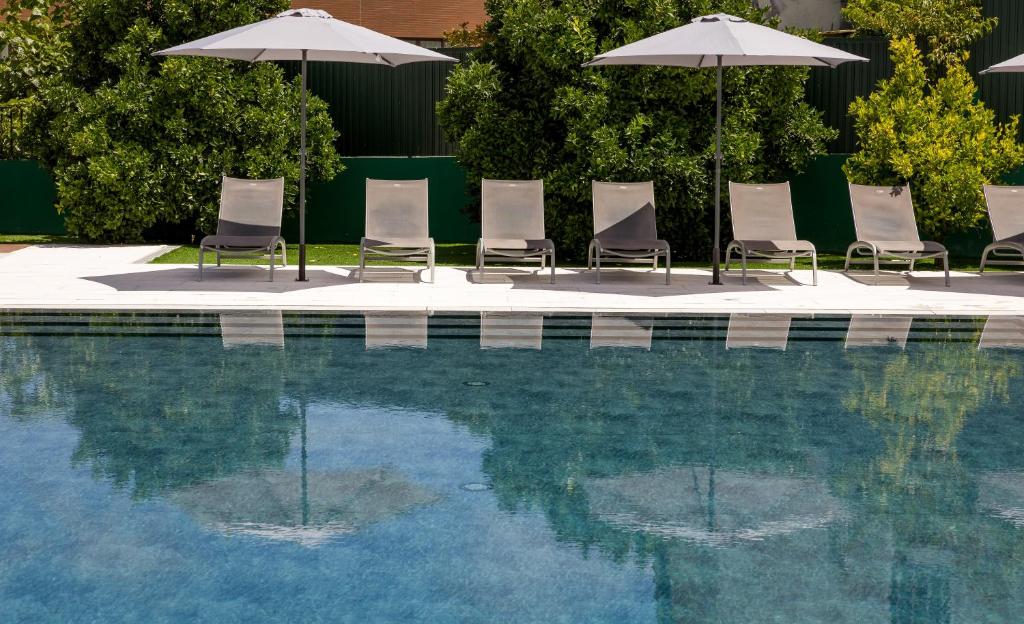 a group of chairs and umbrellas next to a swimming pool at Hotel Do Parque - Congress & SPA in Termas de Sao Pedro do Sul