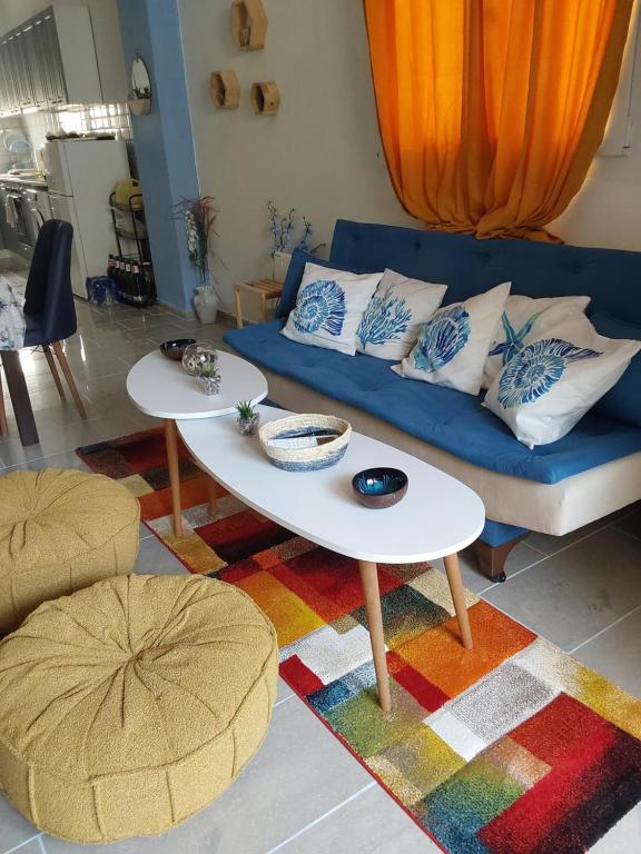 a living room with a blue couch and two tables at Amor de Skioni in Nea Skioni