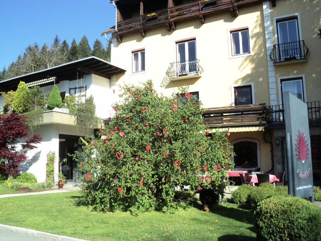 a large tree with red roses in front of a building at Hotel Kürschner in Kötschach